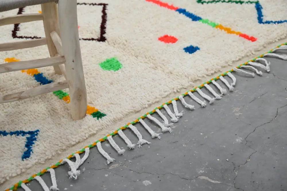 Cream-colored natural wool moroccan azilal rug with colorful geometric patterns and white fringe 253x150 cm