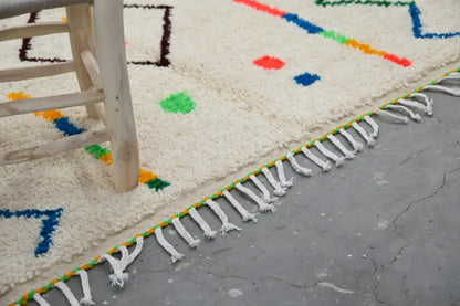 Cream-colored natural wool moroccan azilal rug with colorful geometric patterns and white fringe 253x150 cm