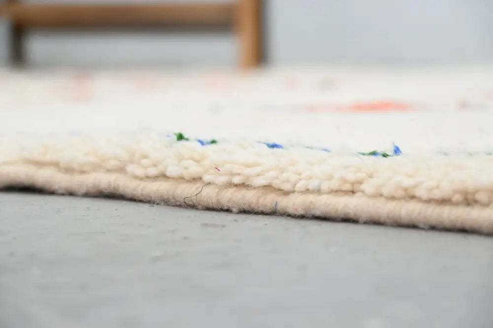 Cream-colored handmade moroccan azilal rug with textured fringed edge and subtle blue and green accents 285x220 cm