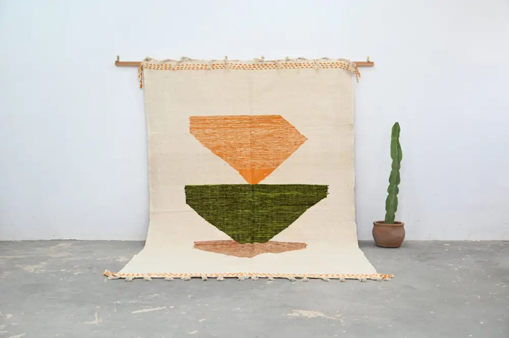 Beige woven handmade moroccan azilal rug featuring geometric orange diamond and green inverted triangle with tan fringe