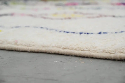 Cream-colored DecorBites™ handmade moroccan azilal rug with soft pile and colorful wavy patterned border 293x206cm