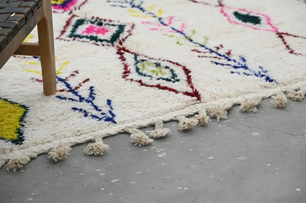 Plush white moroccan azilal rug with colorful geometric patterns and fringed tassel edges handmade by decorbites