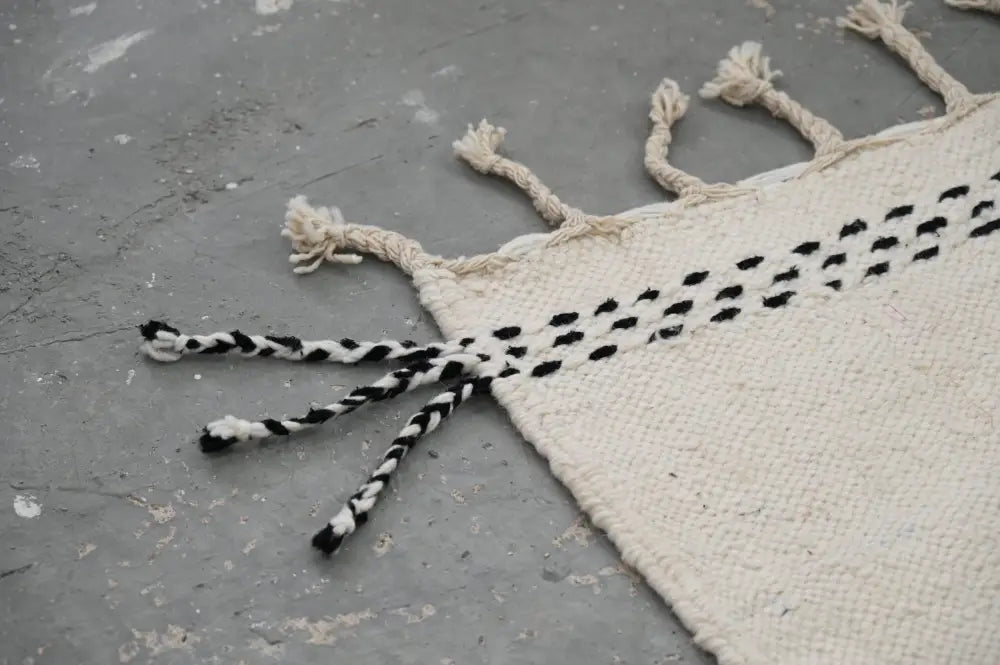 Cream-colored cream-colored woven handmade traditional azilal rug with black dotted pattern and fringed edges by DecorBites