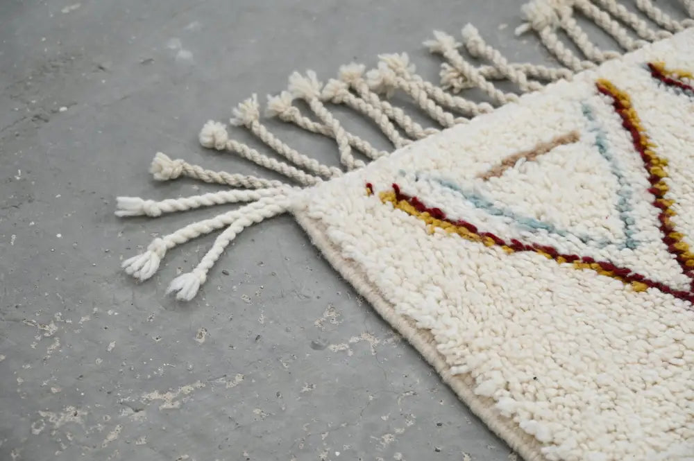 Cream-colored handmade moroccan azilal rug with geometric patterns in earthy tones and white fringe 305x206cm