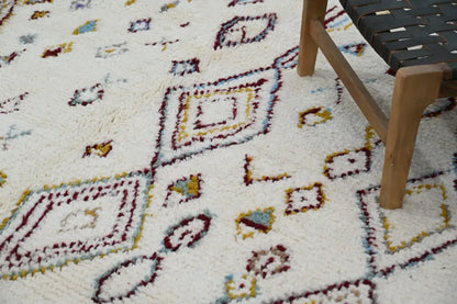 Cream-colored handmade Moroccan Azilal rug with maroon yellow and muted blue geometric patterns 305x206cm by DecorBites