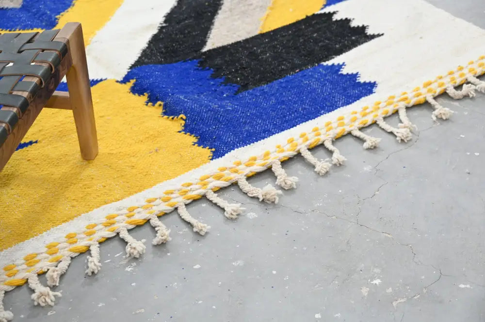 DecorBites™ handmade Moroccan azilal rug with vibrant blue yellow black patterns and cream fringe with woven yellow beads