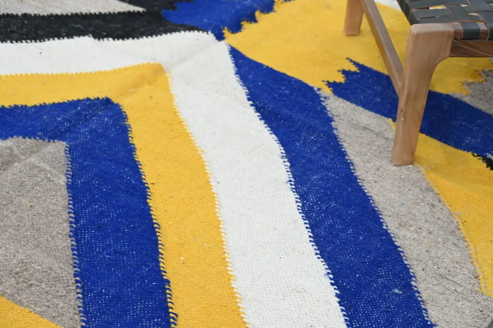 Vibrant handmade Moroccan azilal rug with bold blue yellow and white stripes on a textured woven surface 306x196cm