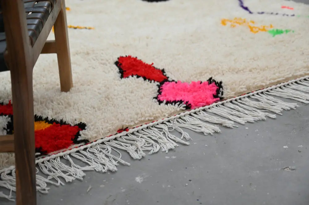 DecorBites™ handmade Moroccan Azilal rug with bold red and pink geometric patterns and white fringe on cream background