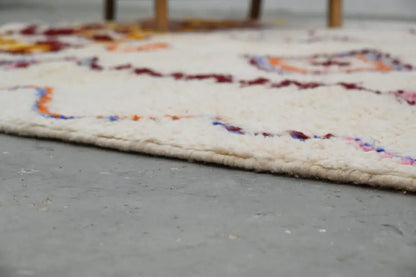 Cream-colored handmade moroccan azilal rug with intricate burgundy orange and blue woven patterns 309x207cm