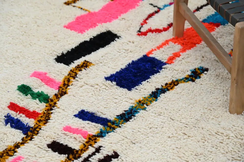 A plush cream-colored decorbites™ handmade moroccan azilal rug with vibrant geometric patterns 313x194cm