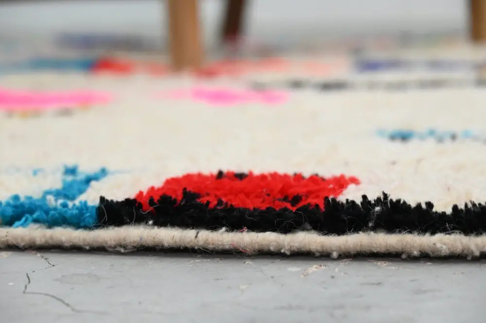 A vibrant handmade moroccan azilal rug with bold red and black geometric patterns on a cream wool background