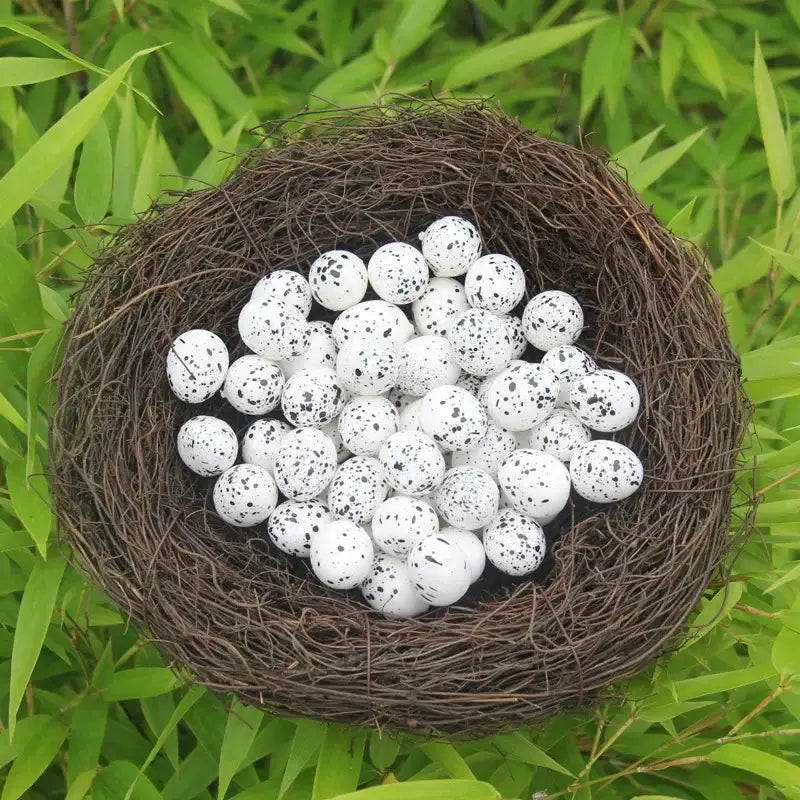 Decorbites™ handmade round rattan bird nest decoration with white eggs speckled in black nestled in green foliage