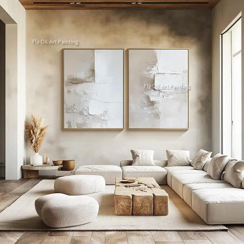 Two canvas wall oil paintings featuring white abstract textured layered surfaces in gold frames on beige wall by decorbites