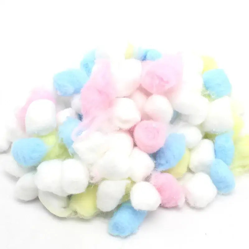A pile of fluffy pastel-colored cotton balls next to a decorbites™ handwoven grass bird cage hut for small birds
