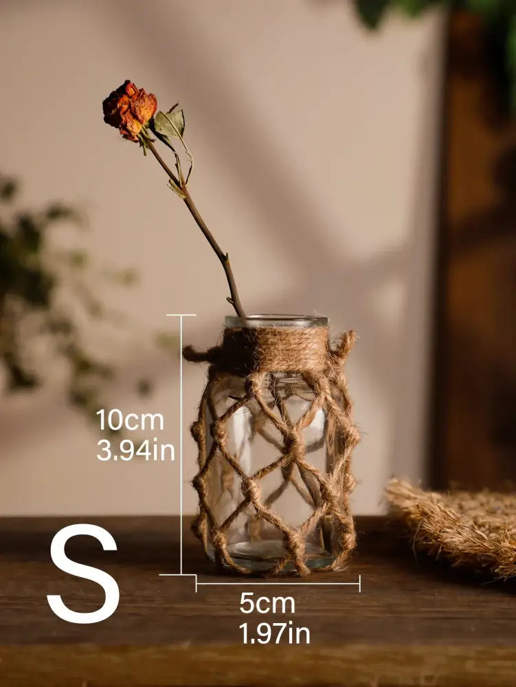A clear hanging glass vase wrapped in rustic hand-woven jute netting with hemp rope for decorbites™ home decor