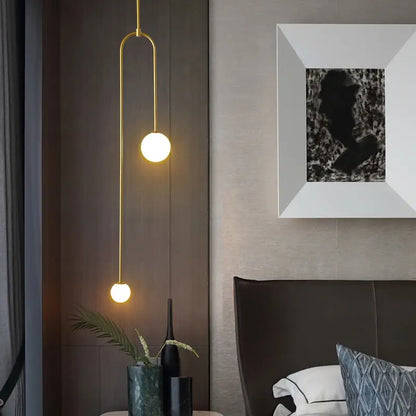 Gold-toned DecorBites™ hanging lights with two spherical glass bulbs on a curved metal arm offer versatile lighting options