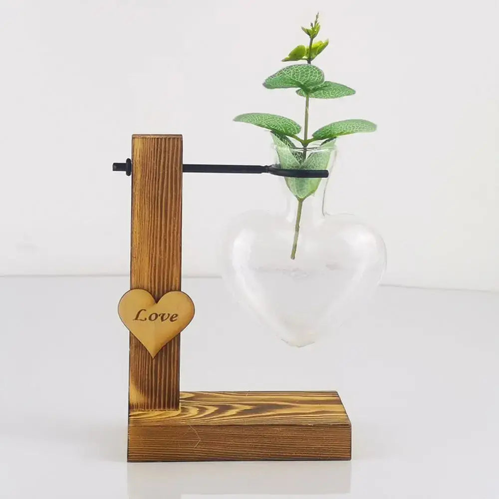 DecorBites™ heart shape hydroponic glass vase with wooden stand holding green leafy plant for home decor