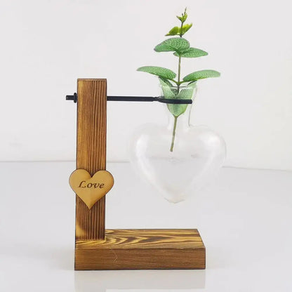 DecorBites™ heart shape hydroponic glass vase with wooden stand holding green leafy plant for home decor