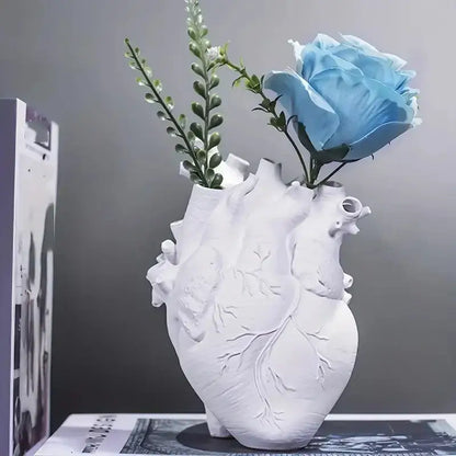 White heart shape resin vase with detailed vein carvings holding a light blue rose and greenery by DecorBites™