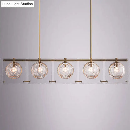 Modern five-light island light fixture with brass finish and clear faceted glass ball globes by decorbites