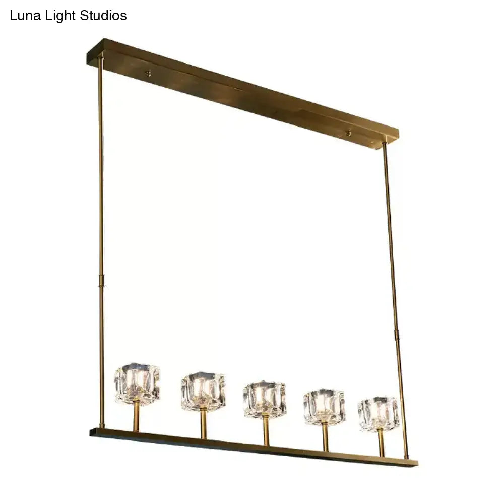 Gold-toned rectangular pendant light with five faceted crystal glass shades and bulb base for dining room use