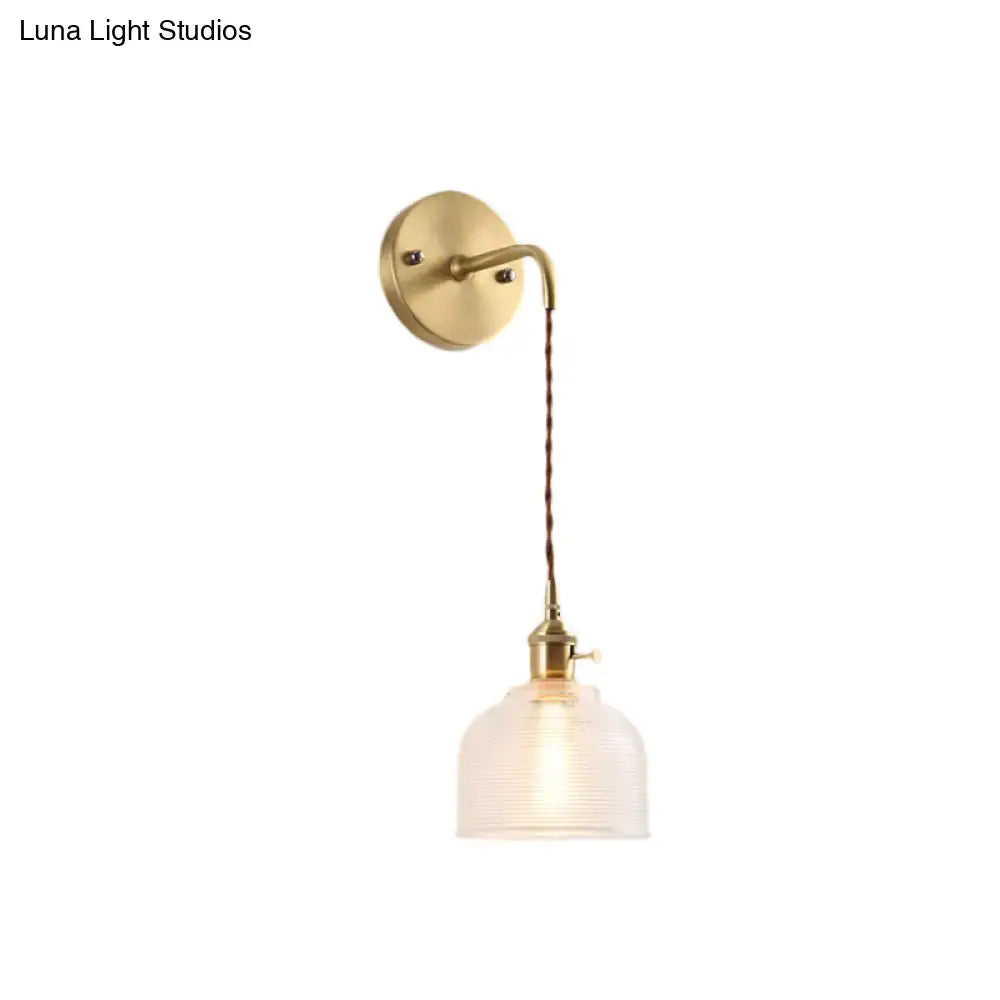 Industrial brass sconce with textured glass dome featuring a brass finish and braided cord for bedroom lighting