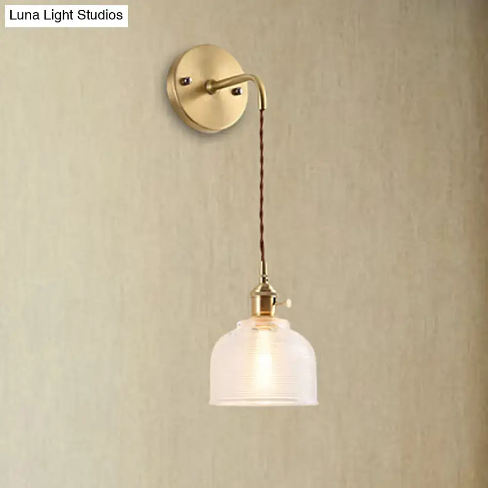 Vintage-style industrial brass sconce with a textured glass dome and braided cord for bedroom lighting