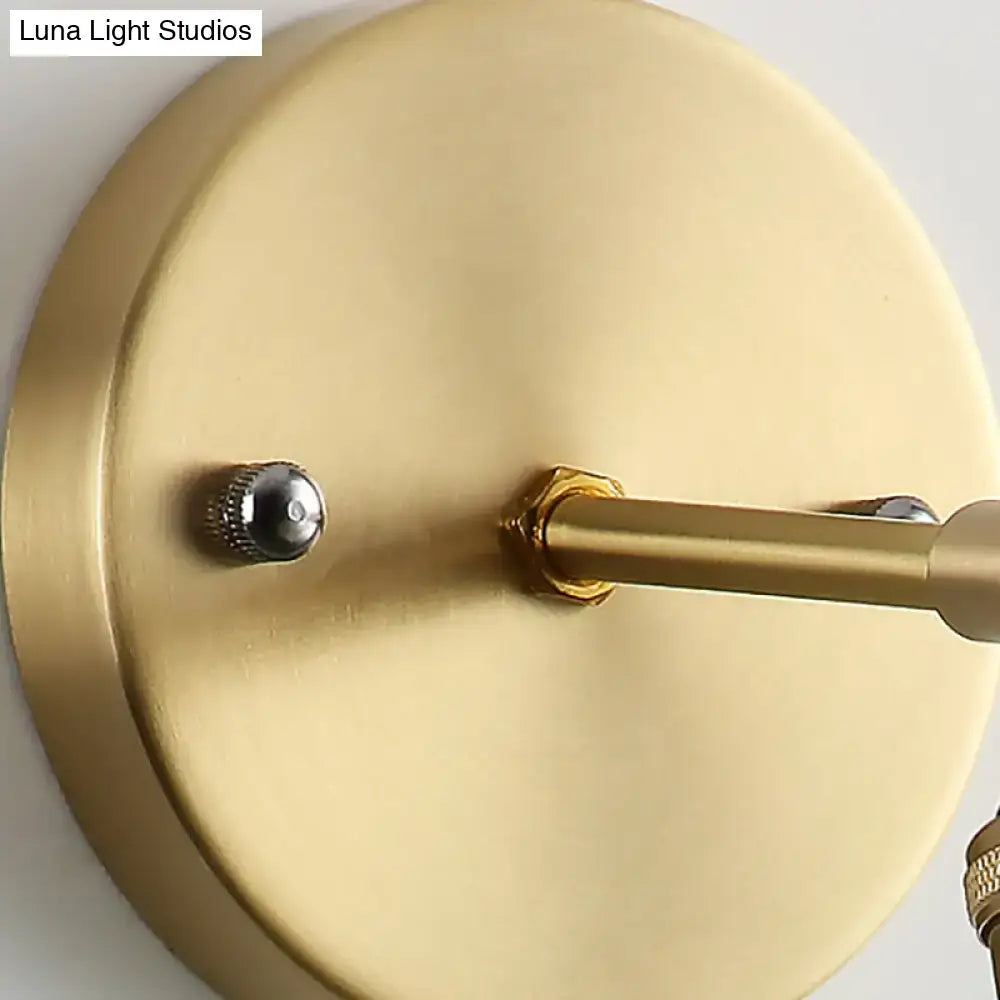Industrial brass sconce with gold-toned brushed metal finish and textured glass dome for bedroom lighting