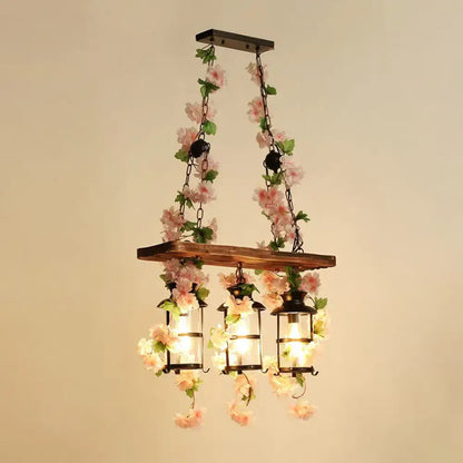 A rustic wooden cage island pendant light with black metal lanterns and pink plant decoration for restaurant lighting
