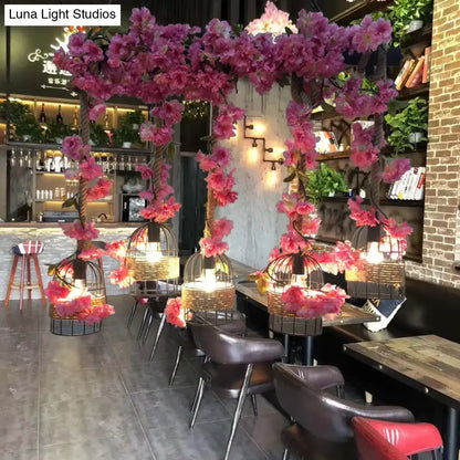 Pink artificial cherry blossoms frame ornate black industrial metal ceiling lamp birdcage pendant fixture height