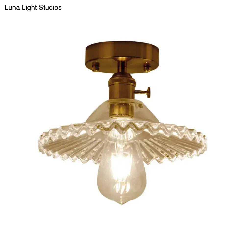 Brass-finished one-light ceiling light with clear scalloped ribbed glass shade and exposed bulb by decorbites