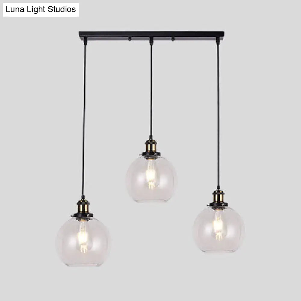 Black metal bar with three clear glass globe pendant lights hanging from cords in industrial style brass round barn admix kit
