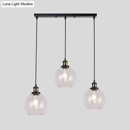 Black metal bar with three clear glass globe pendant lights hanging from cords in industrial style brass round barn admix kit