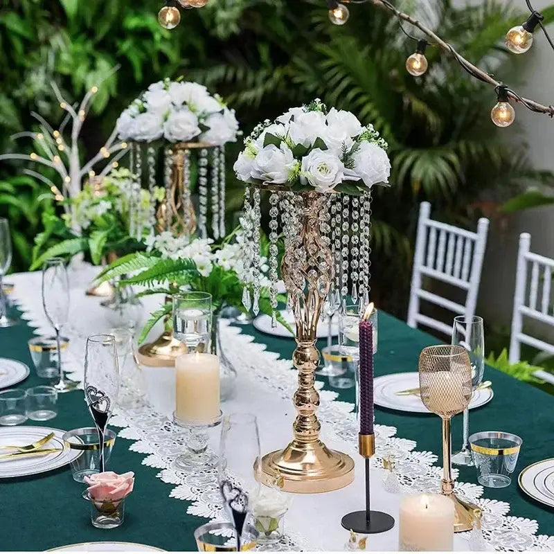 Gold-colored crystal chandelier centerpiece with cascading clear beads and white floral arrangement in iron flower racks