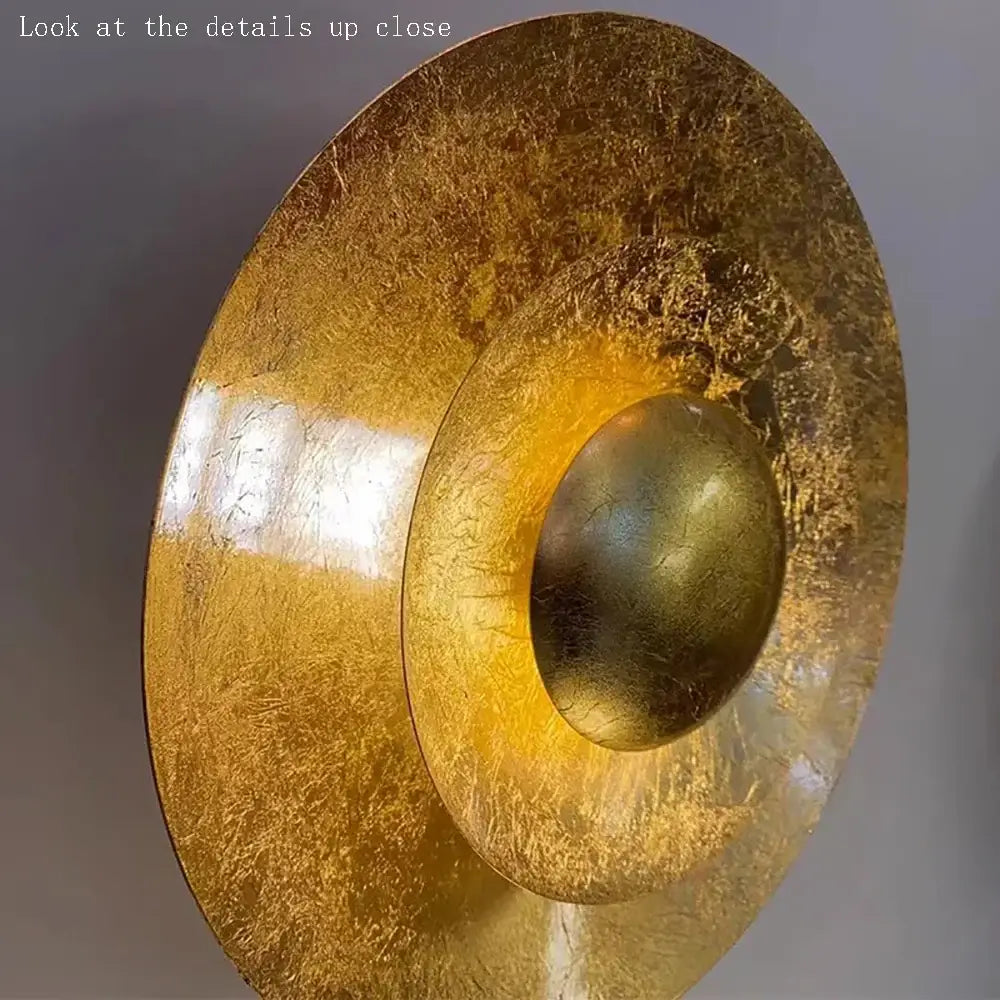 A textured golden metallic wall sconce with a circular concave design from decorbites italian vintage art collection