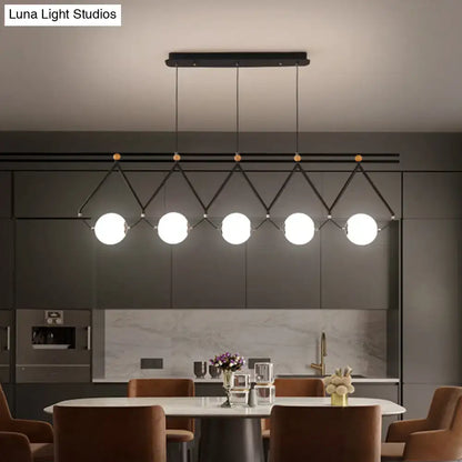 Modern black metal suspension light with five white glass balls in a geometric diamond pattern by DecorBites™