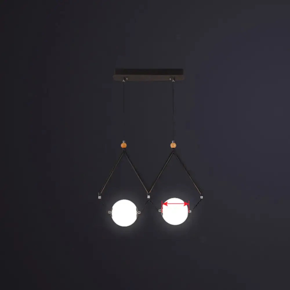 Modern black metal suspension light with two glowing ivory glass spheres in minimalist ball restaurant suspension design