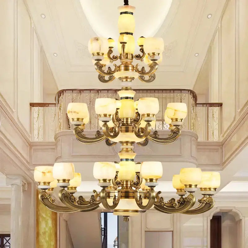 A three-tiered decorbites jade chandelier with ornate bronze metalwork and cream glass shades for living room use