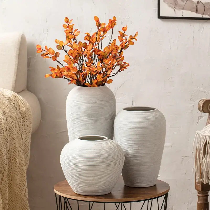 Three white ceramic minimalist hydroponic vases with textured ribbed surfaces on a wooden table by DecorBites