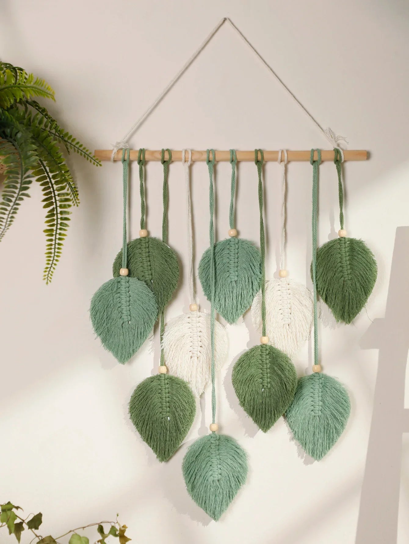 DecorBites™ macrame wall hanging with green and white woven leaves on brown wooden rod for boho home decor