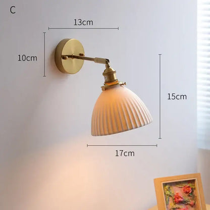 A warm-toned ribbed glass decorbites led ceramic wall sconce with brass finish and adjustable arm for bedroom lighting