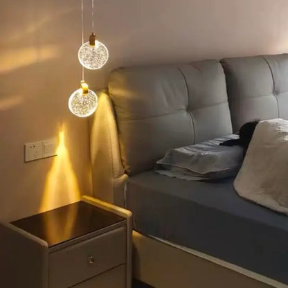Two clear glass decorbites™ led crystal pendant lights with golden metal fixtures for bedroom and bathroom use
