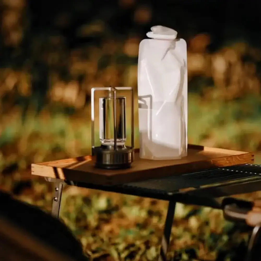 White collapsible water bottle with white cap made of flexible plastic beside decorbites led crystal table lamp