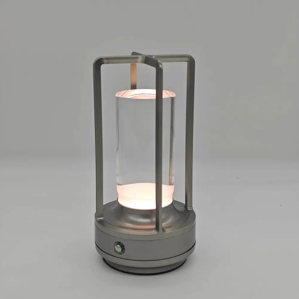 A sleek modern DecorBites™ led crystal table lamp with metallic frame and glass cylinder for bedside use
