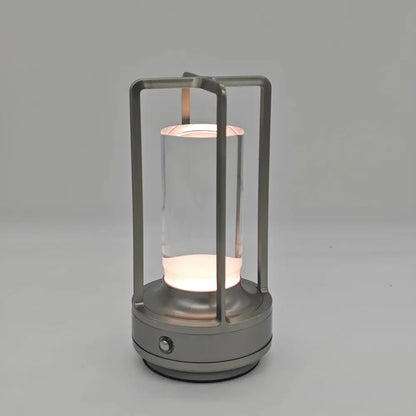 A sleek modern DecorBites™ led crystal table lamp with metallic frame and glass cylinder for bedside use