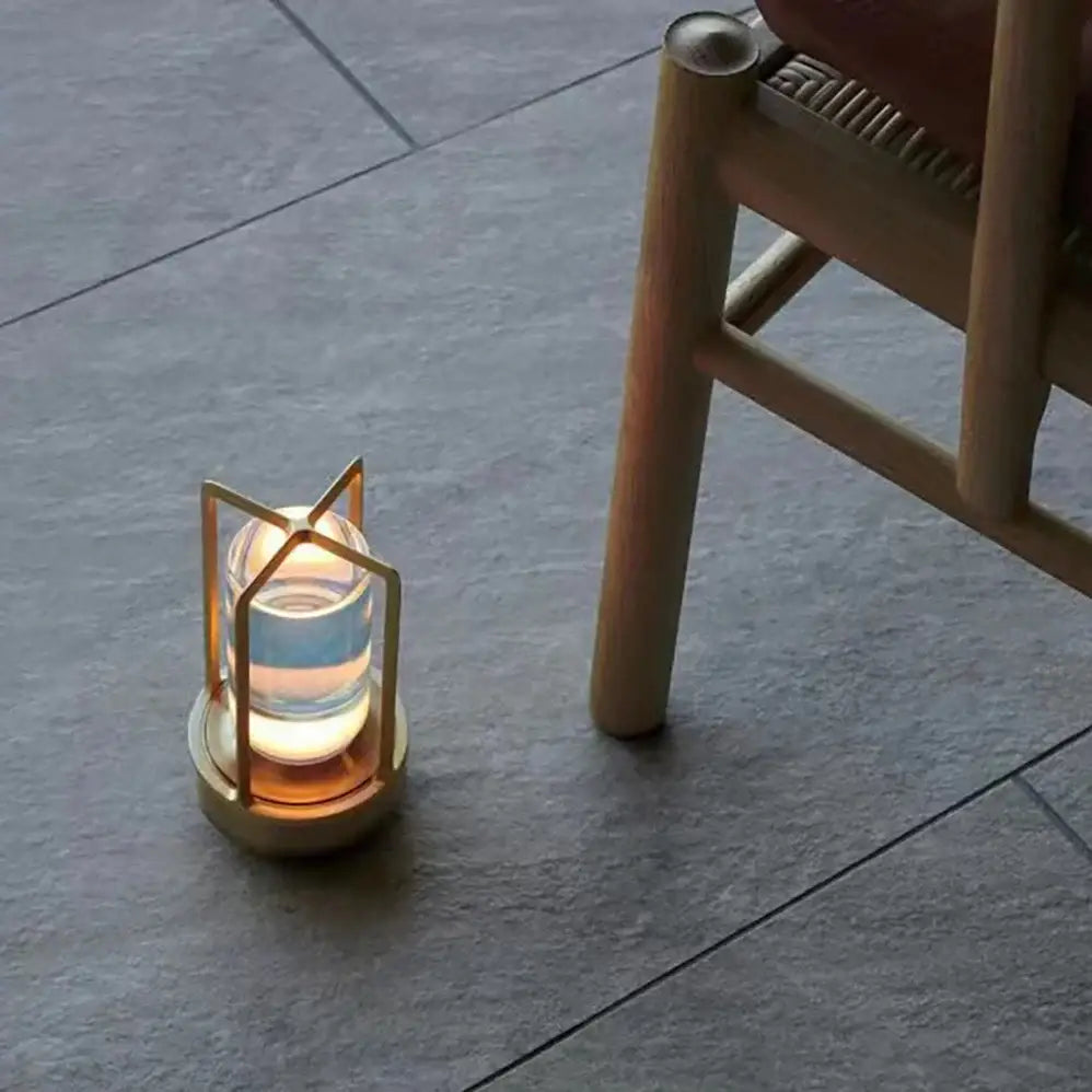 A sleek brass decorbites™ led crystal table lamp with clear glass housing an illuminated candle for bedside use