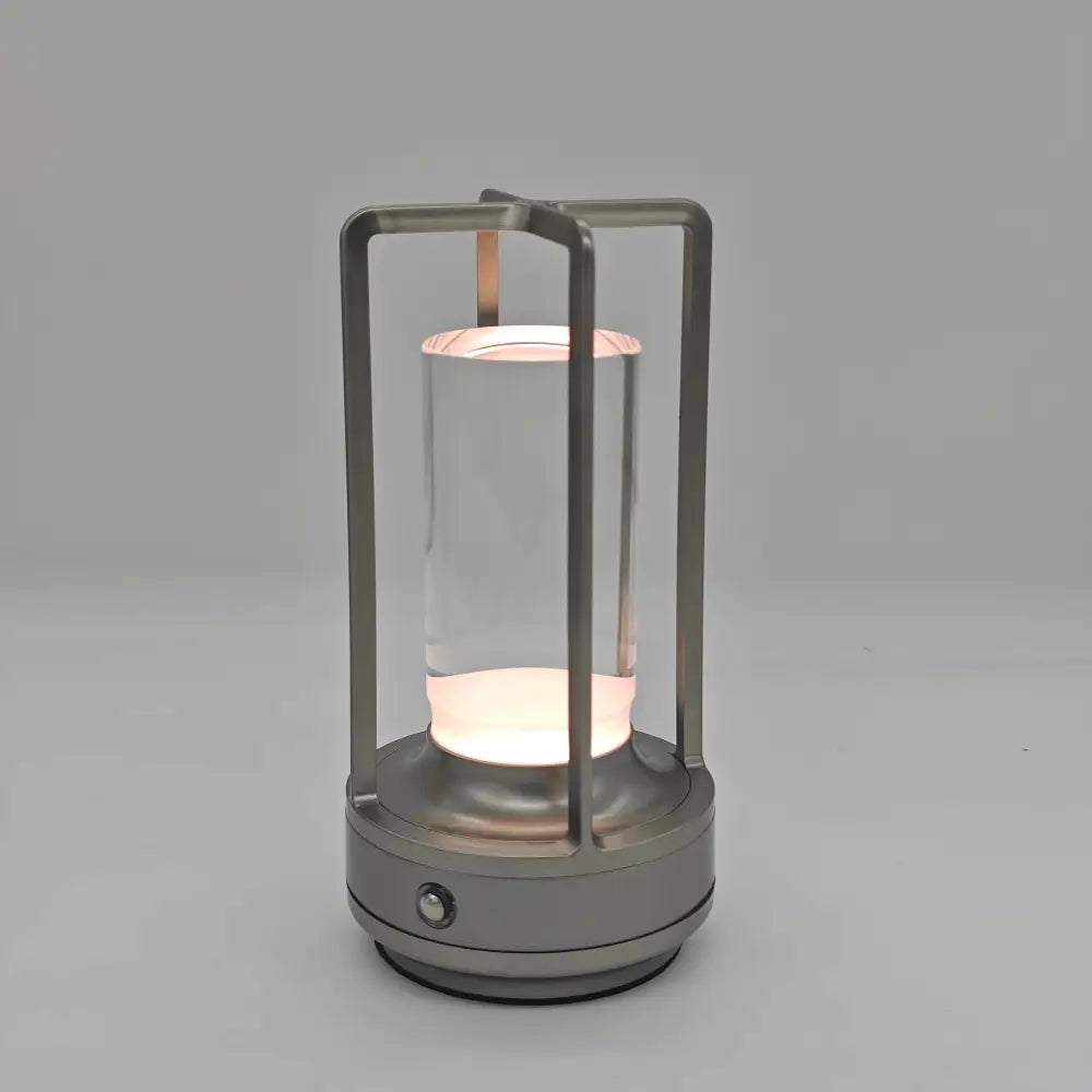 A sleek silver metallic frame led crystal table lamp with clear glass and rechargeable touch light for bedside use