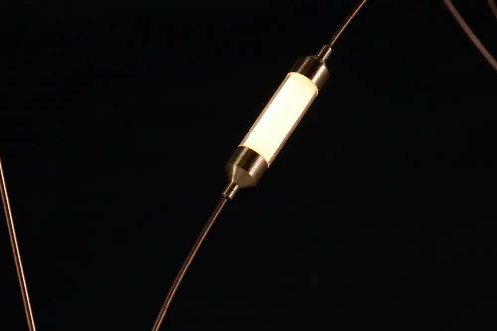 A sleek cylindrical led firefly chandelier with warm white glow and metallic ends showcasing engineering minimal design