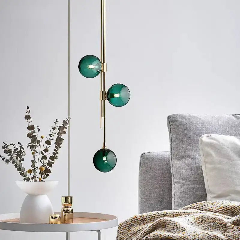 Modern pendant light featuring three emerald green glass ball spheres on a brass rod by decorbites led glass