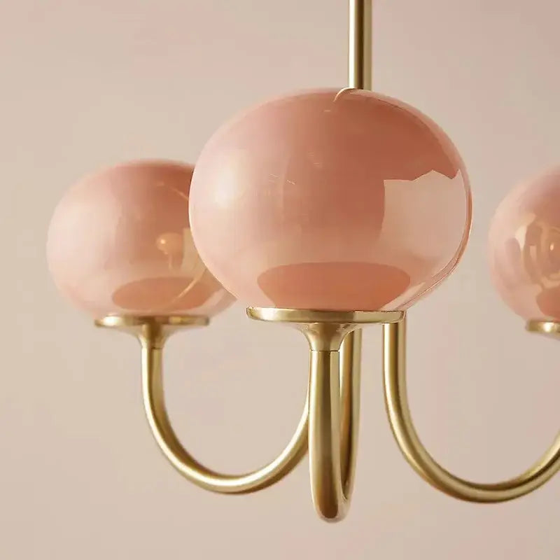 A decorbites led glass chandelier with three pink translucent glass balls and polished brass arms for home decor